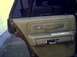 1987 Ford Crown Victoria LTD - The interior door panel of a car shows a tan fabric and vinyl design with chrome accents and a pull handle.