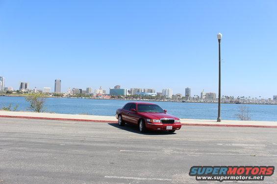 2002 Mercury Grand Marquis parked near a body of water with a city skyline