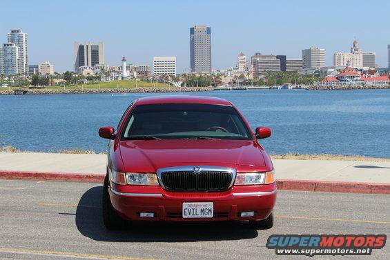 Red 2002 Mercury Grand Marquis parked by the water with city skyline