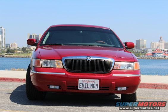 Red 2002 Mercury Grand Marquis with custom license plate 'EVIL MGM' parked by the water