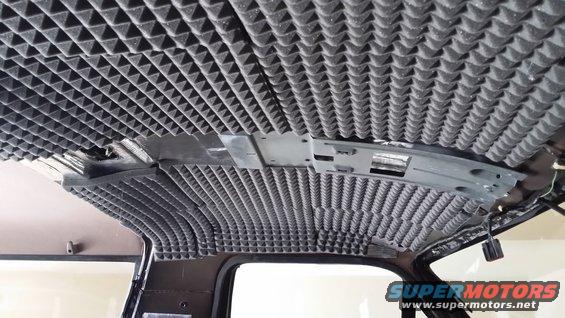 Vehicle interior ceiling covered in pyramid-shaped soundproofing foam, with exposed wiring and mounting brackets