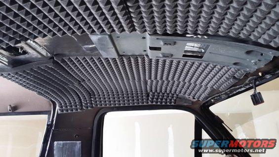 Vehicle ceiling covered in pyramid-shaped soundproofing foam, showing exposed metal structure and wiring