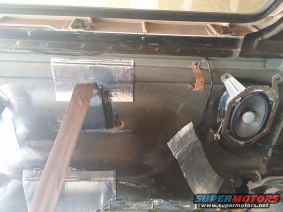 Interior door panel with speaker removed, showing soundproofing material and seatbelt