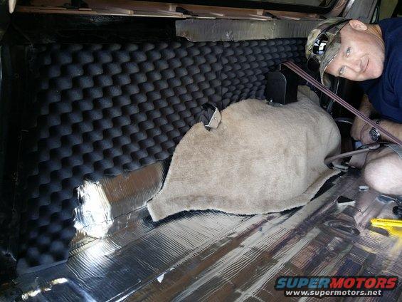 guy installing soundproofing foam and foil in back of vehicle