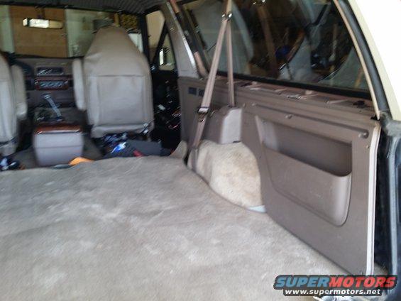 Interior of a tan 1992 Ford Bronco with carpeted floor and rear cargo area, showing front seats and door panel