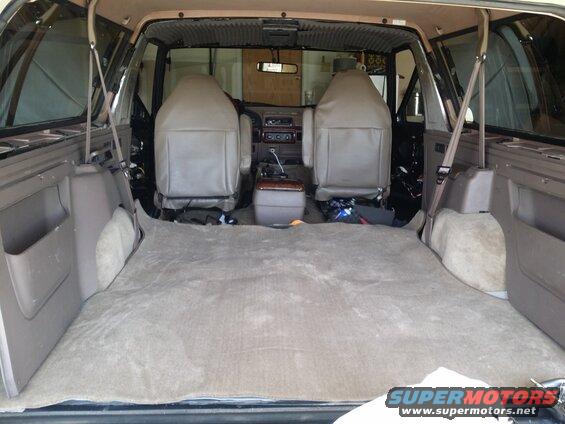Interior view of a 1992 Ford Bronco with seats removed and carpet pulled back, showing disassembled interior panels