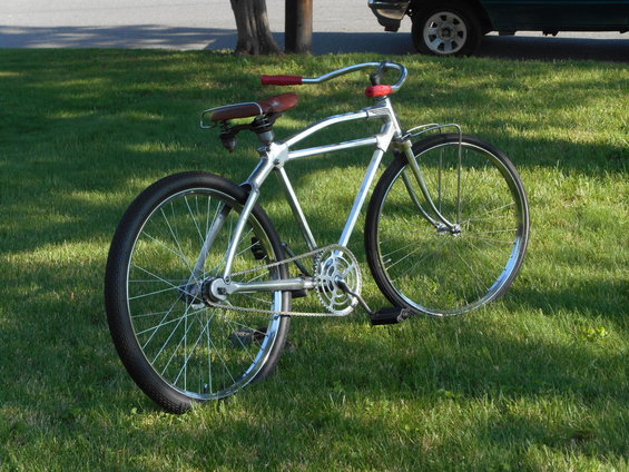 Chrome bicycle with red handlebars and brown seat on grass