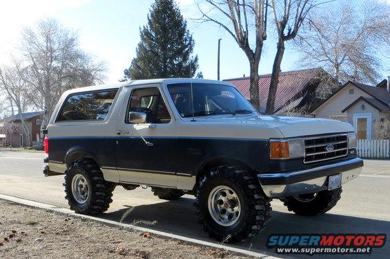 Two-tone Ford Bronco with large off-road tires parked on a street