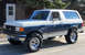 1989 Ford Bronco - This lifted Ford Bronco features a two-tone paint scheme and aggressive off-road tires.