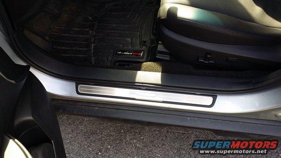Silver door sill with horizontal lines and a black WeatherTech floor mat inside a car