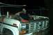 1979 Ford Bronco - Man takes a break with a drink while working on the engine of a 1979 Ford Bronco.