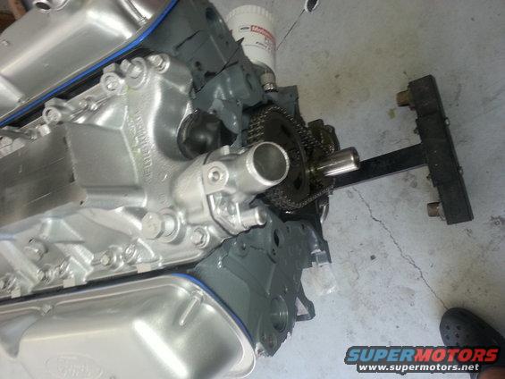 Ford engine block with timing chain and oil filter visible. Supermotors.net logo in corner