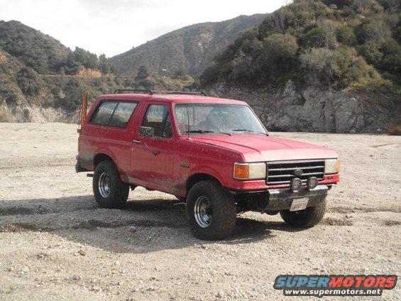 1988 Ford Bronco parked on dirt road with mountains in background