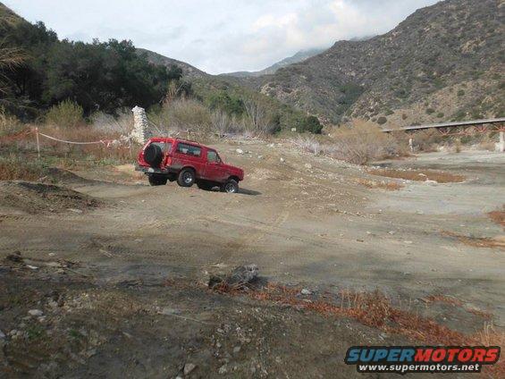 Red 1988 Ford Bronco on dirt road, spare tire on rear door