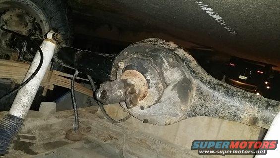 Rear axle assembly with driveshaft U-joint and shock absorber