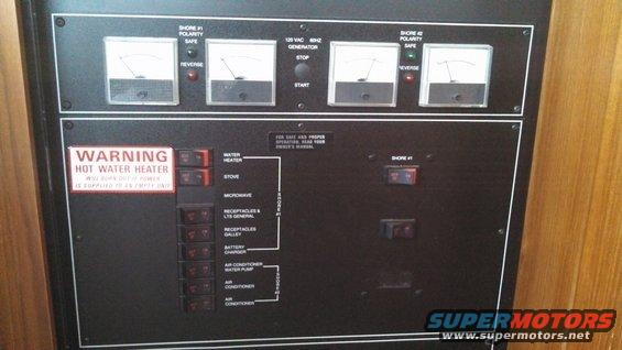 Boat electrical panel with gauges, switches, and warning labels for hot water heater