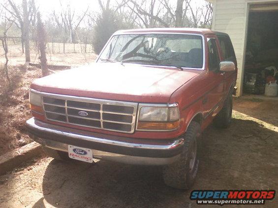 Red 1992 Ford Bronco parked in front of a garage