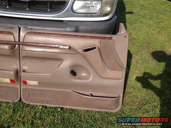 Tan interior door panels with wood trim, next to a vehicle grille