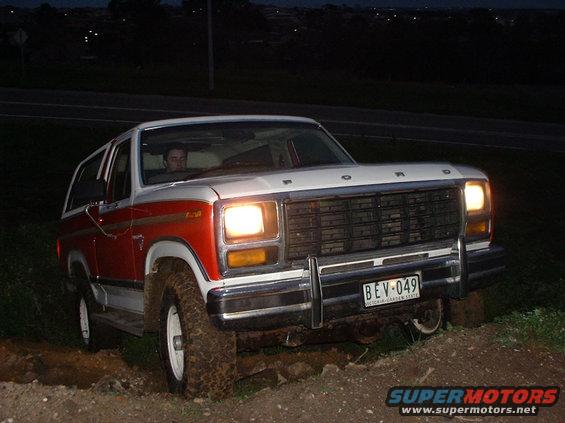 White and red 1980s Ford Bronco front view, license plate BEV-049