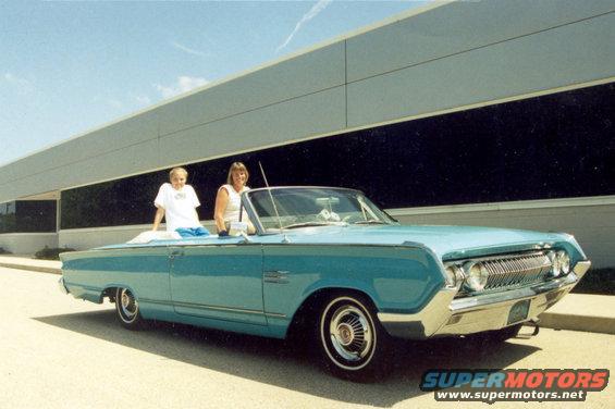 Blue 1964 Mercury Monterey convertible parked outside a modern building