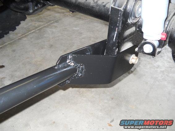 Close-up of a black metal suspension bracket attached to a vehicle's axle and shock absorber