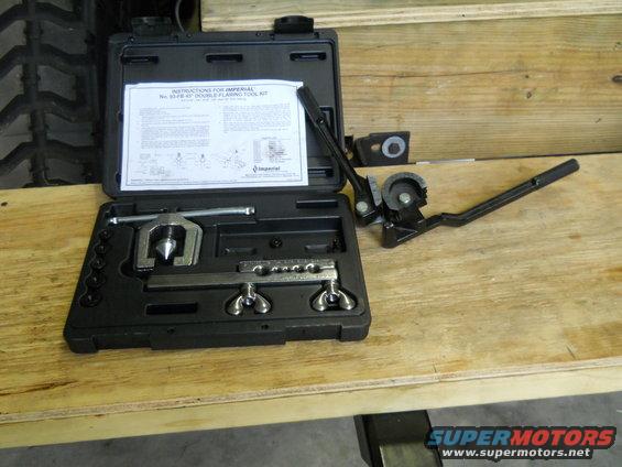 Double flaring tool kit with instructions on a wooden surface. Tire tread visible in background