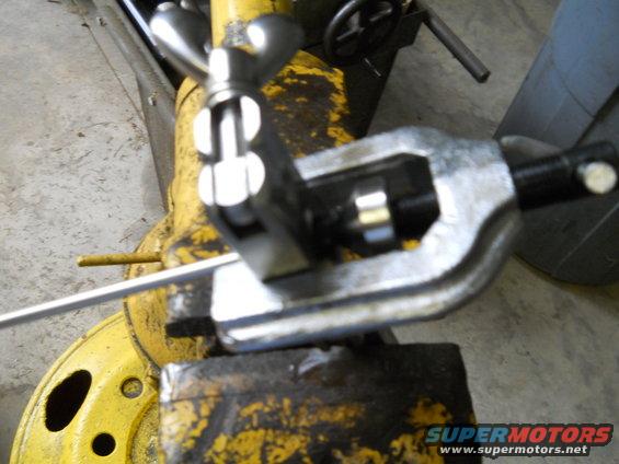 Tubing bender tool on yellow machinery with Supermotors logo