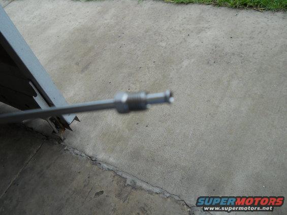 metal cable end with threaded fitting, on concrete with grass in background