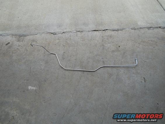 Metal fuel line bent into shape, lying on a concrete surface