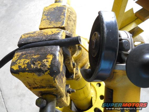 Black hose held in yellow vise, with angle grinder nearby. Text on hose reads 'Made in USA'