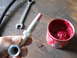 1992 Ford Bronco - A grease gun fitting is held in hand next to a wrench and a can of red grease, suggesting maintenance work.