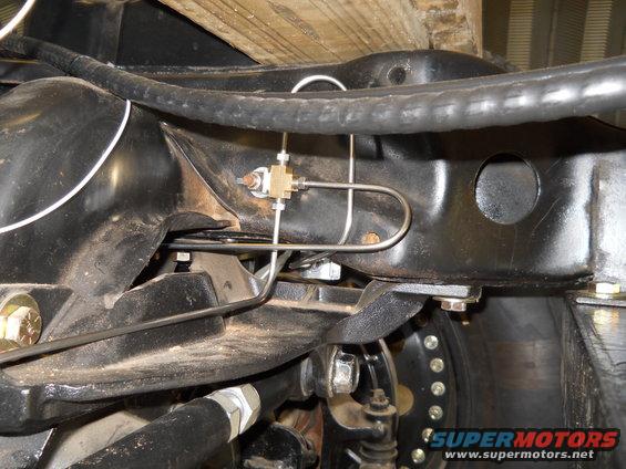 Underbody view of brake lines and suspension components with Supermotors.net watermark