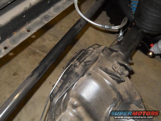 Close-up of a dirty transmission housing with metal lines and part of the vehicle frame