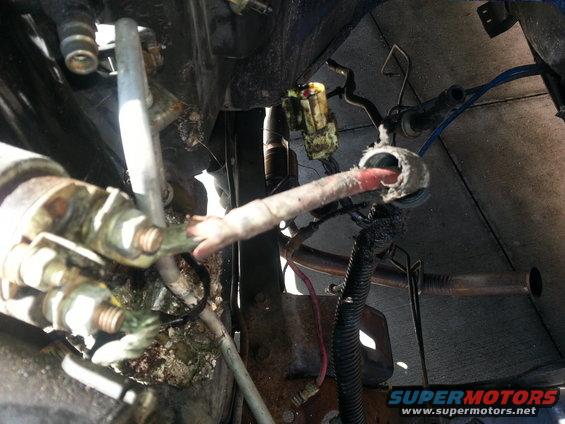 Engine starter motor with corroded terminals and frayed wiring, viewed from below
