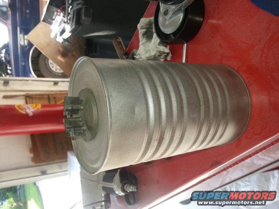 Exhaust muffler with splined shaft on one end, resting on a red surface