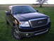 2007 Ford F-150 - A dark blue Ford F-150 pickup truck is shown from a three-quarter front angle, parked outdoors on a sunny day.