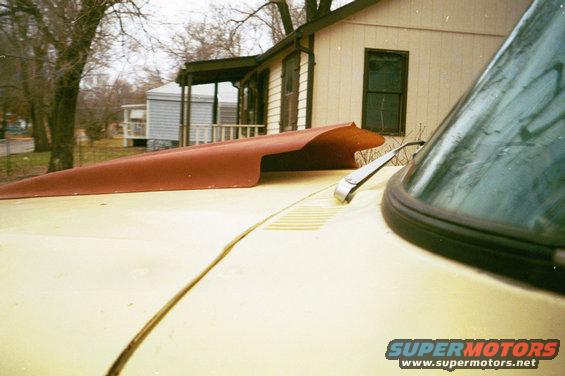 Yellow car hood with a red aftermarket hood scoop and a windshield wiper