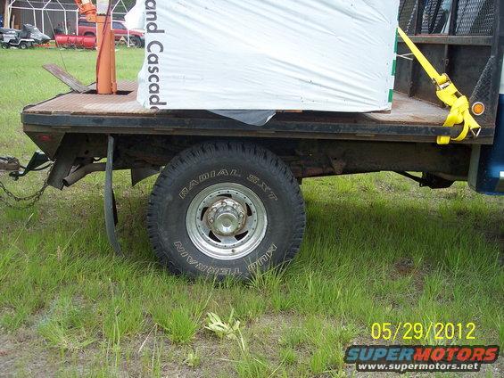 Flatbed truck side view, loaded with white material secured by yellow strap