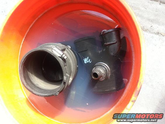 Engine intake parts soaking in a bucket of water