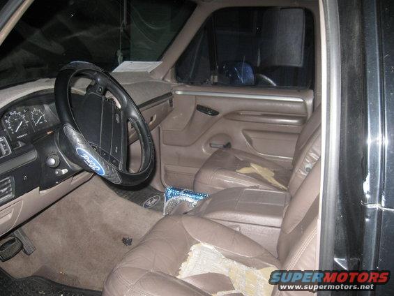 Interior of a truck with worn brown leather seats and a Ford steering wheel cover