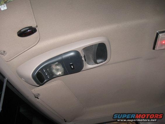 Overhead console with light, switch, and speaker grille in a vehicle interior