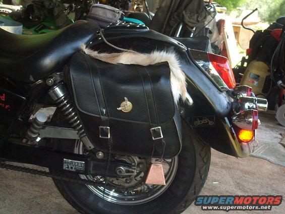 Motorcycle rear fender with black saddlebag, fur trim, and cowbell
