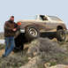 1989 Ford Bronco - A man poses with a muddy 1989 Ford Bronco navigating rocky terrain.