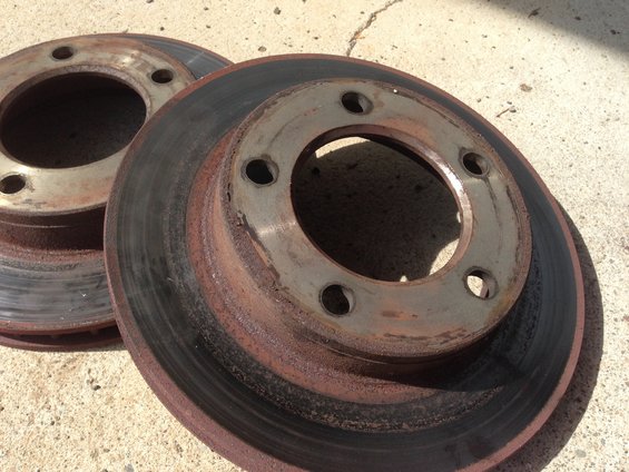 Two rusty brake rotors stacked on concrete