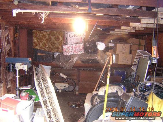 cluttered garage with drill press, boxes, bike parts, and a shopping cart