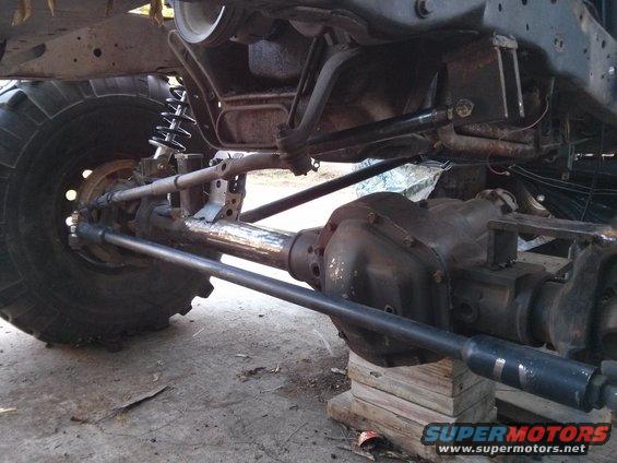Undercarriage of a modified vehicle showing a large tire, differential, and suspension components