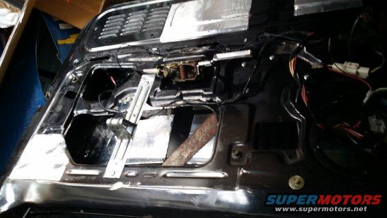 Car door interior with window mechanism and wiring exposed, showing soundproofing material