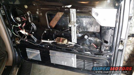 Car door interior with soundproofing material and exposed wiring