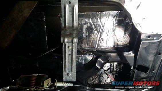 Interior of a car door showing metal structure, wiring, and silver soundproofing material applied to the panel
