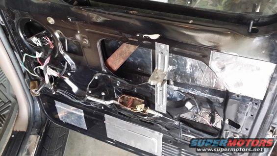 Car door interior with soundproofing material and exposed wiring
